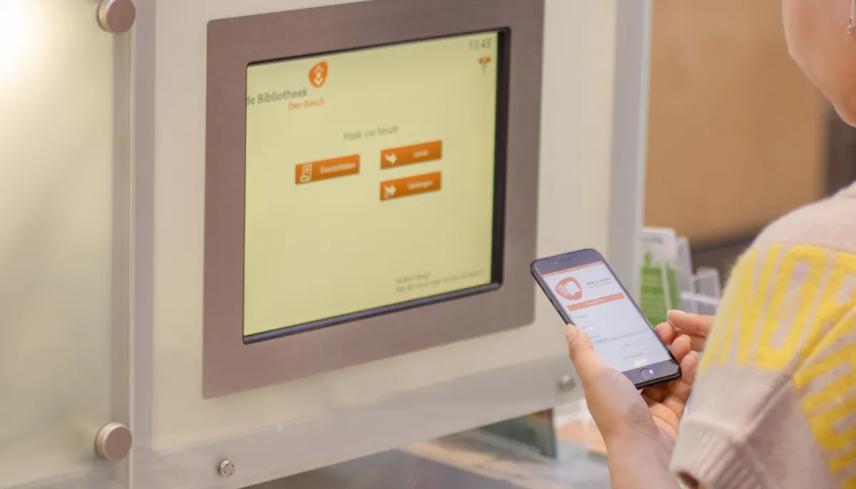 Meisje bij uitleenbalie met telefoon in hand_BiebApp