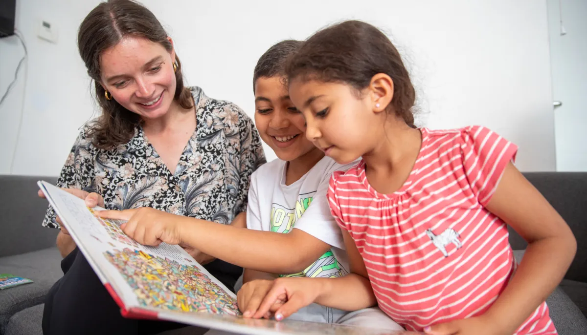 vrouw bekijkt boek met twee kinderen