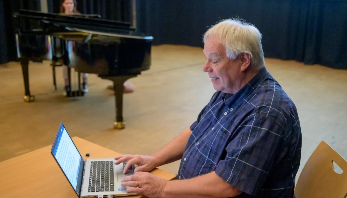man achter laptop in zaal 
