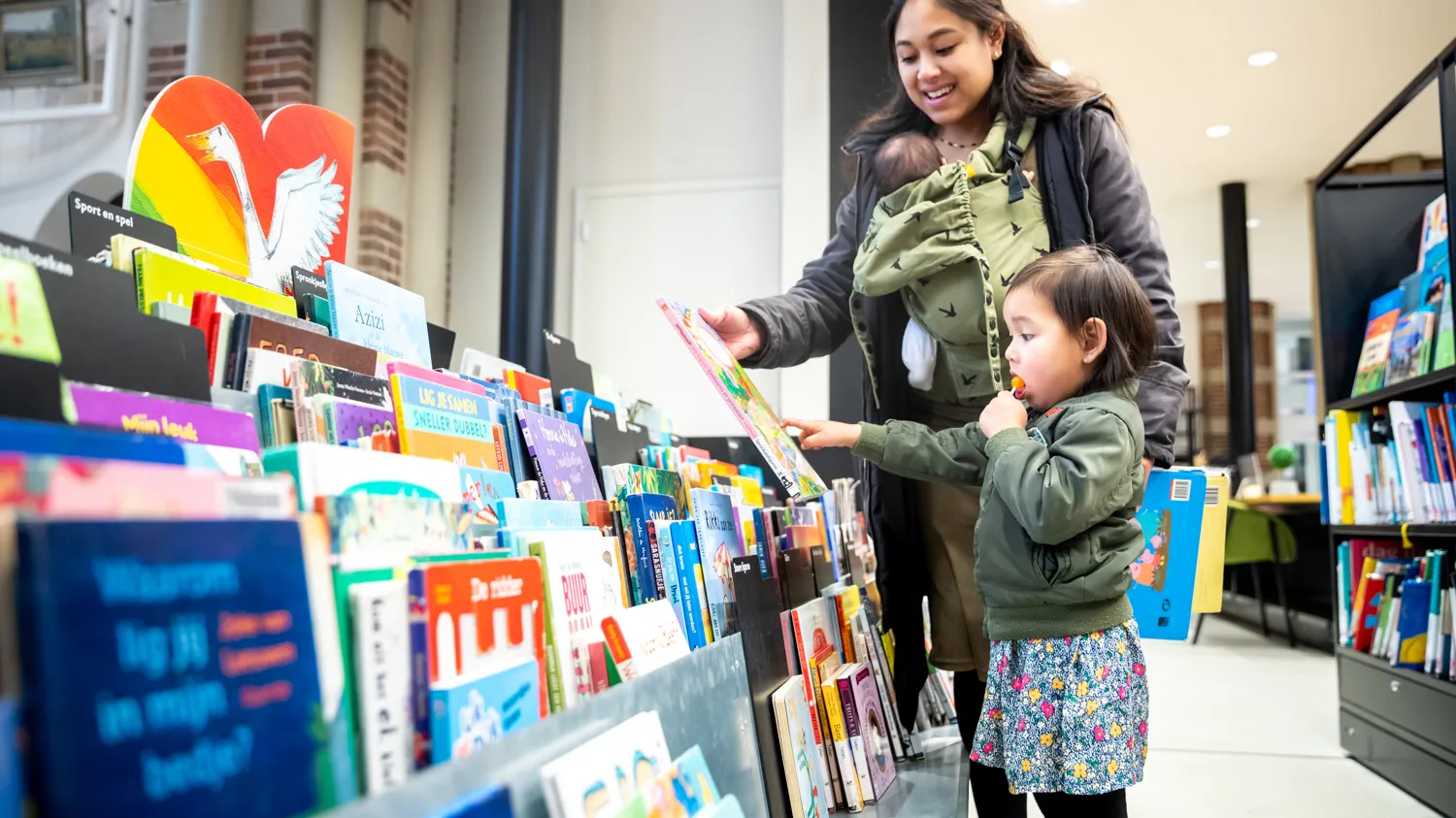 Moeder en kind zoeken boeken in kast bij DePetrus