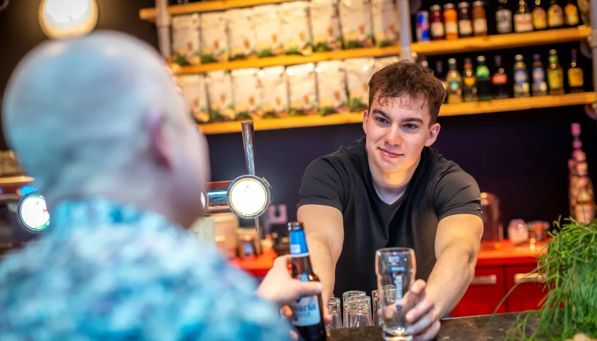 Jongen achter bar serveert biertje uit