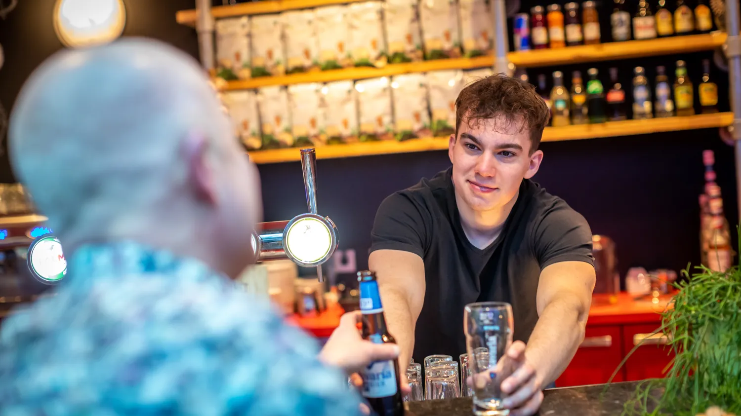 Jongen achter bar serveert biertje uit