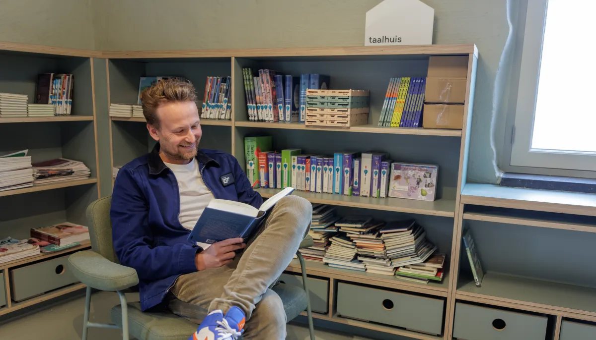 Man in stoel met een boek in het taalhuis