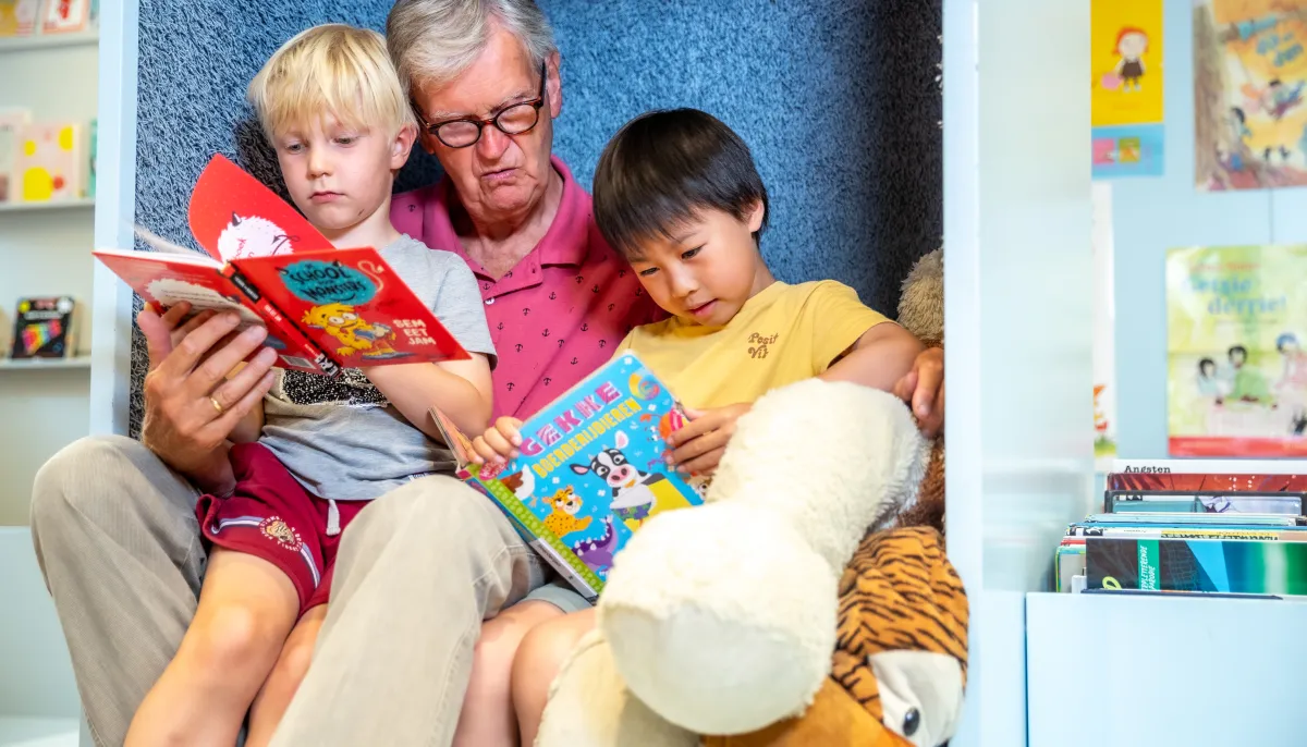 man met 2 jongetjes die in boeken kijken 