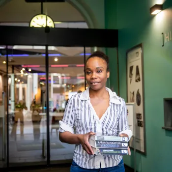 vrouw in ingang met stapel boeken