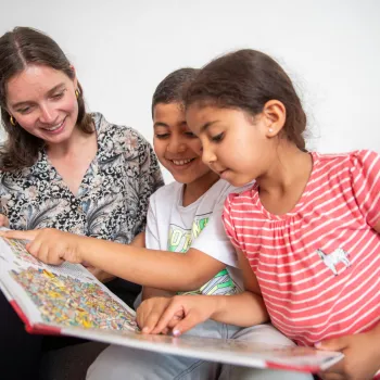vrouw bekijkt boek met twee kinderen