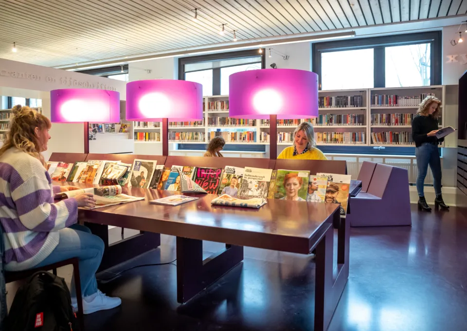 mensen rond leestafel met paarse lampen