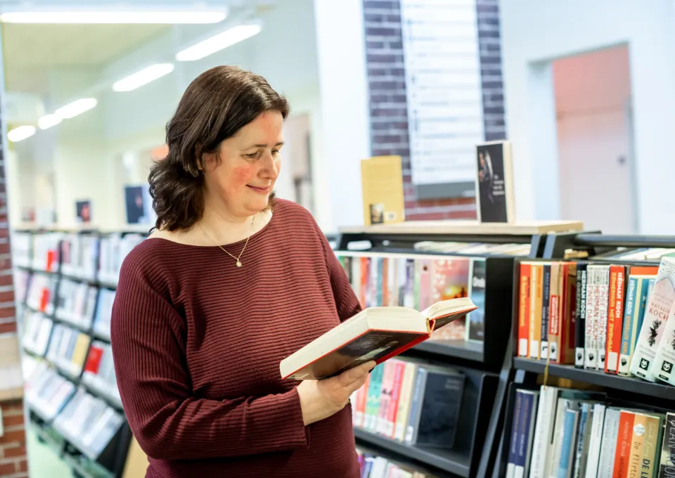 vrouw met boek voor boekenkast