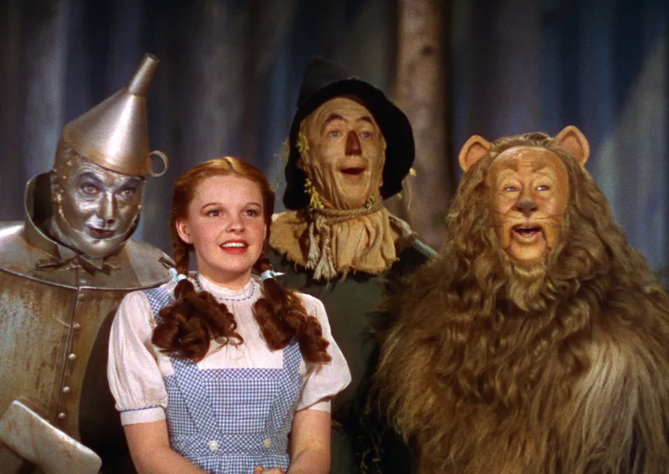 de vier hoofdpersonages van de wizard of oz kijken vrolijk