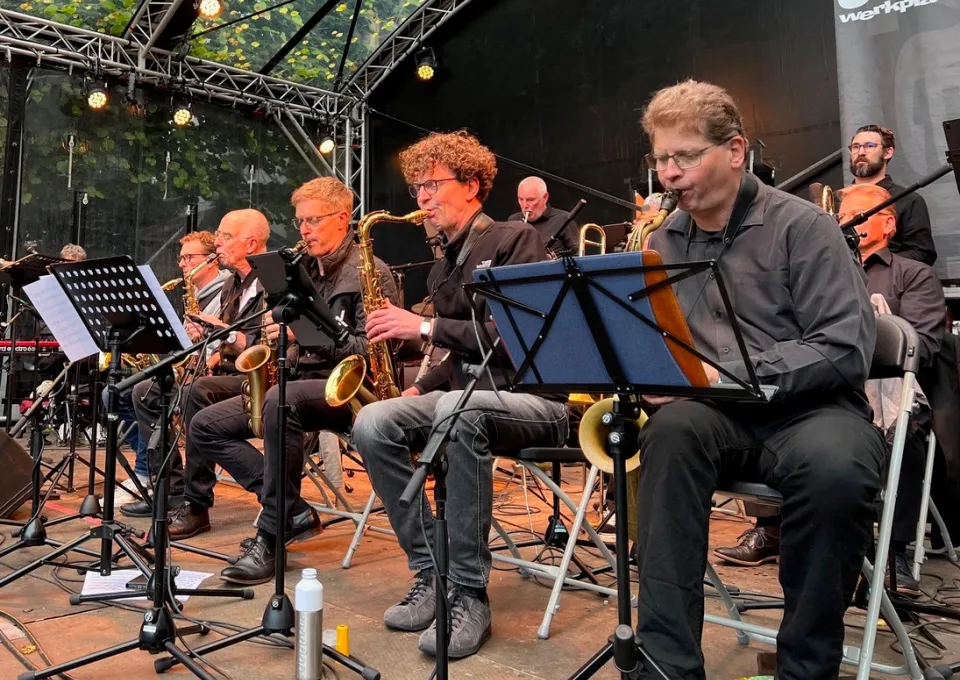 Big band op podium zittend op stoel met instrumenten