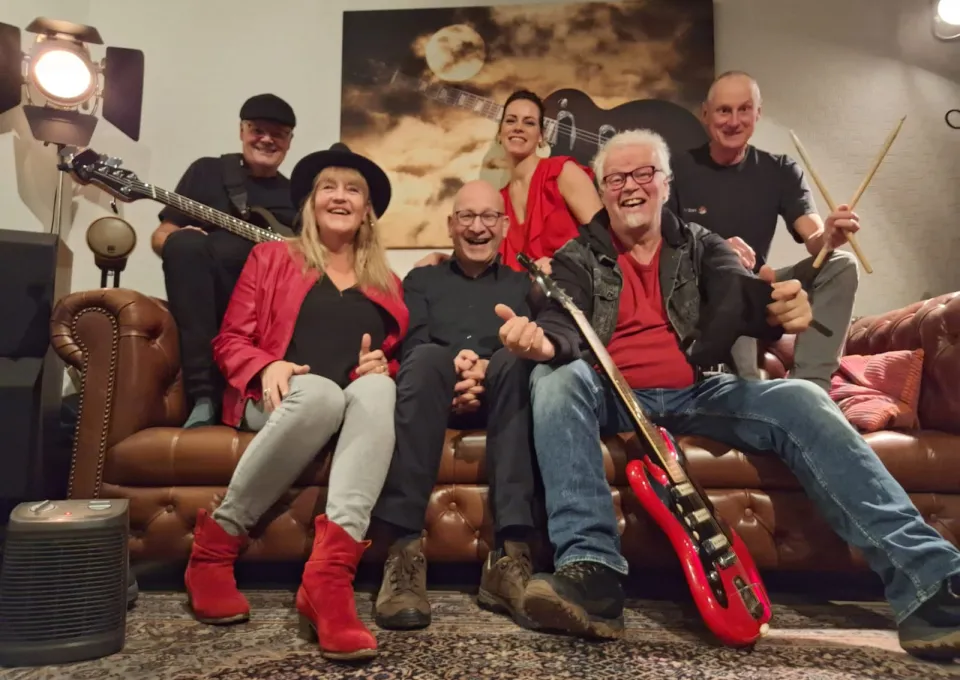 Bandleden met instrumenten zittend op bank