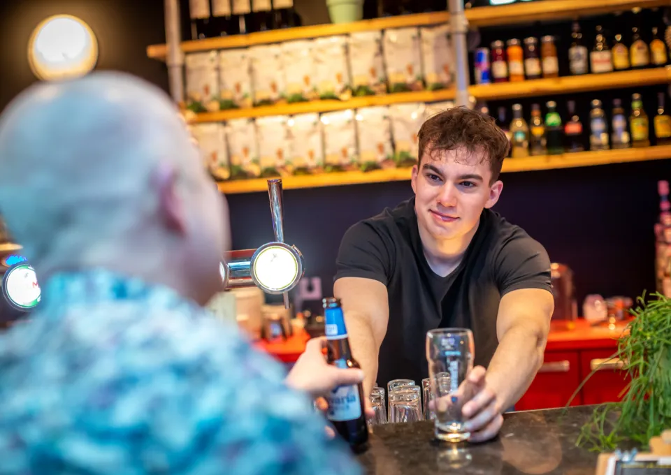 Jongen achter bar serveert biertje uit