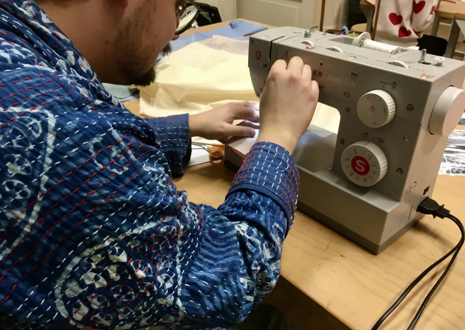 Man achter naaimachine