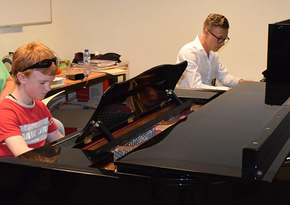 Man en leerling achter piano