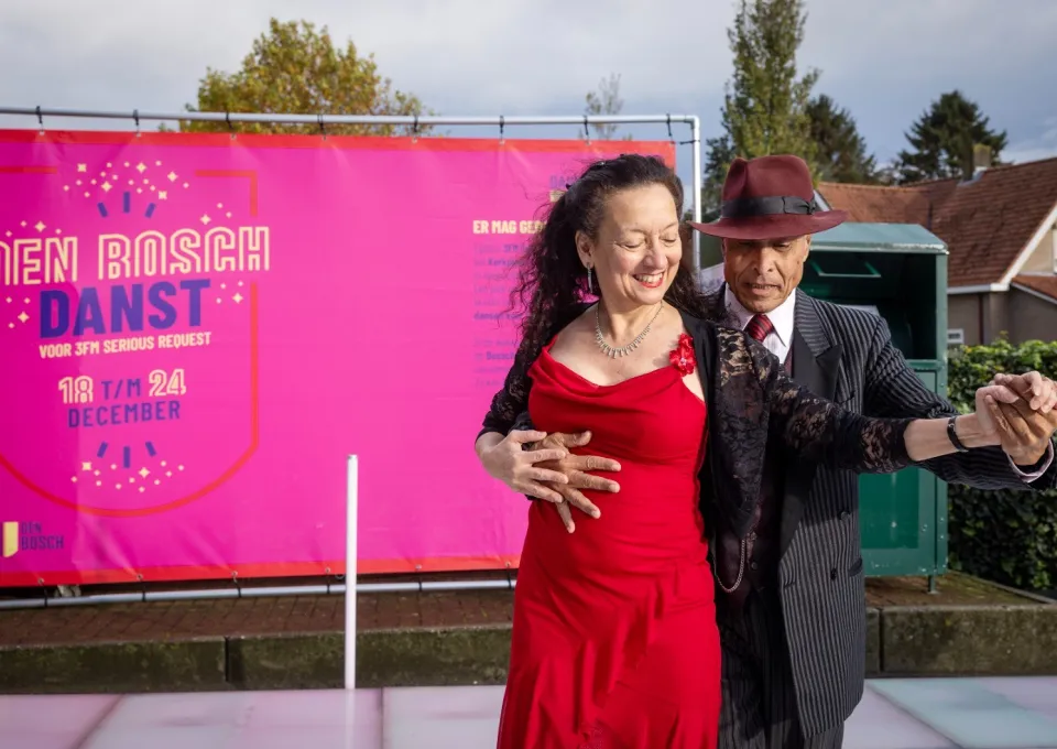 man met hoed en vrouw in rode jurk dansen tango