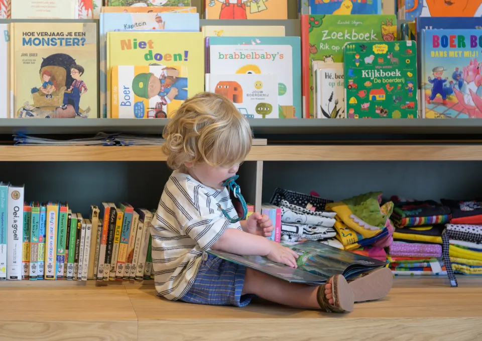 peuter zit voor boekenkast