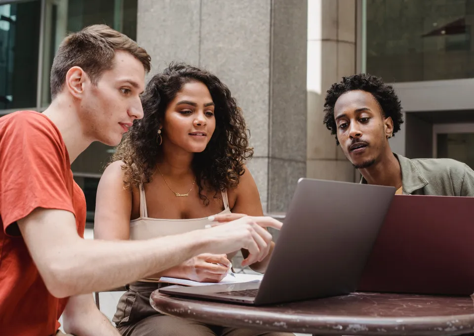 Drie jongeren die samen naar een laptopscherm kijken