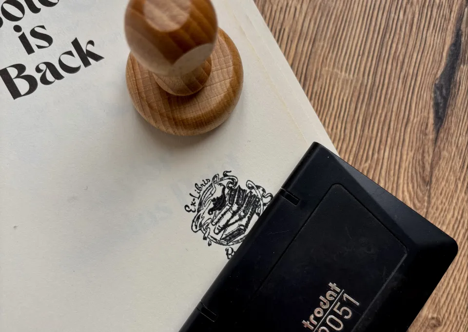 pagina van boek met boekenstempel ex libris, inktpad en houten stempel