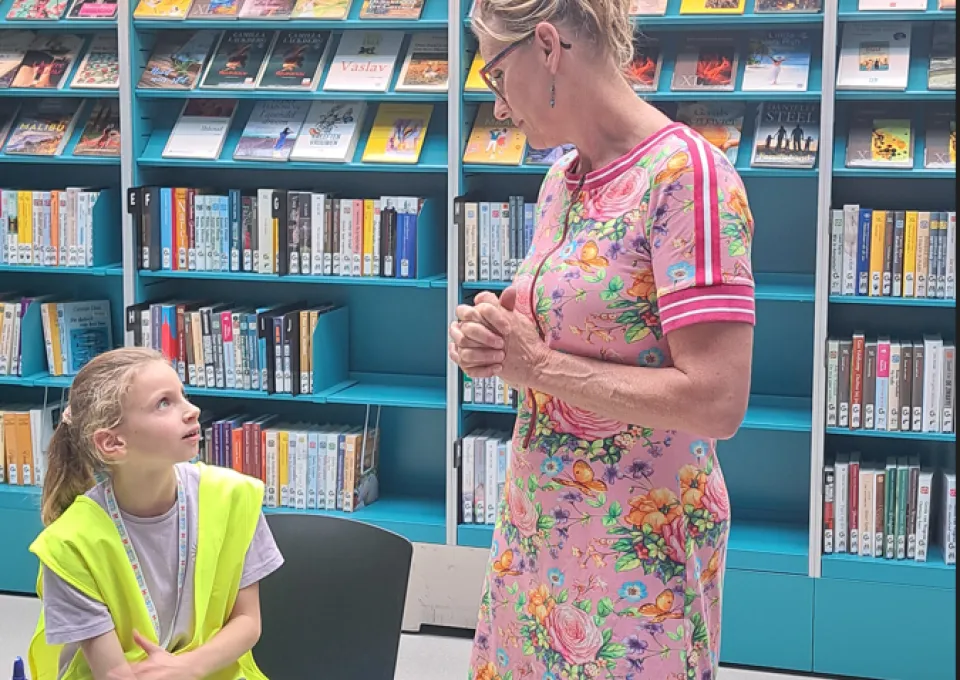 zittend meisje in gesprek met vrouw voor boekenkast