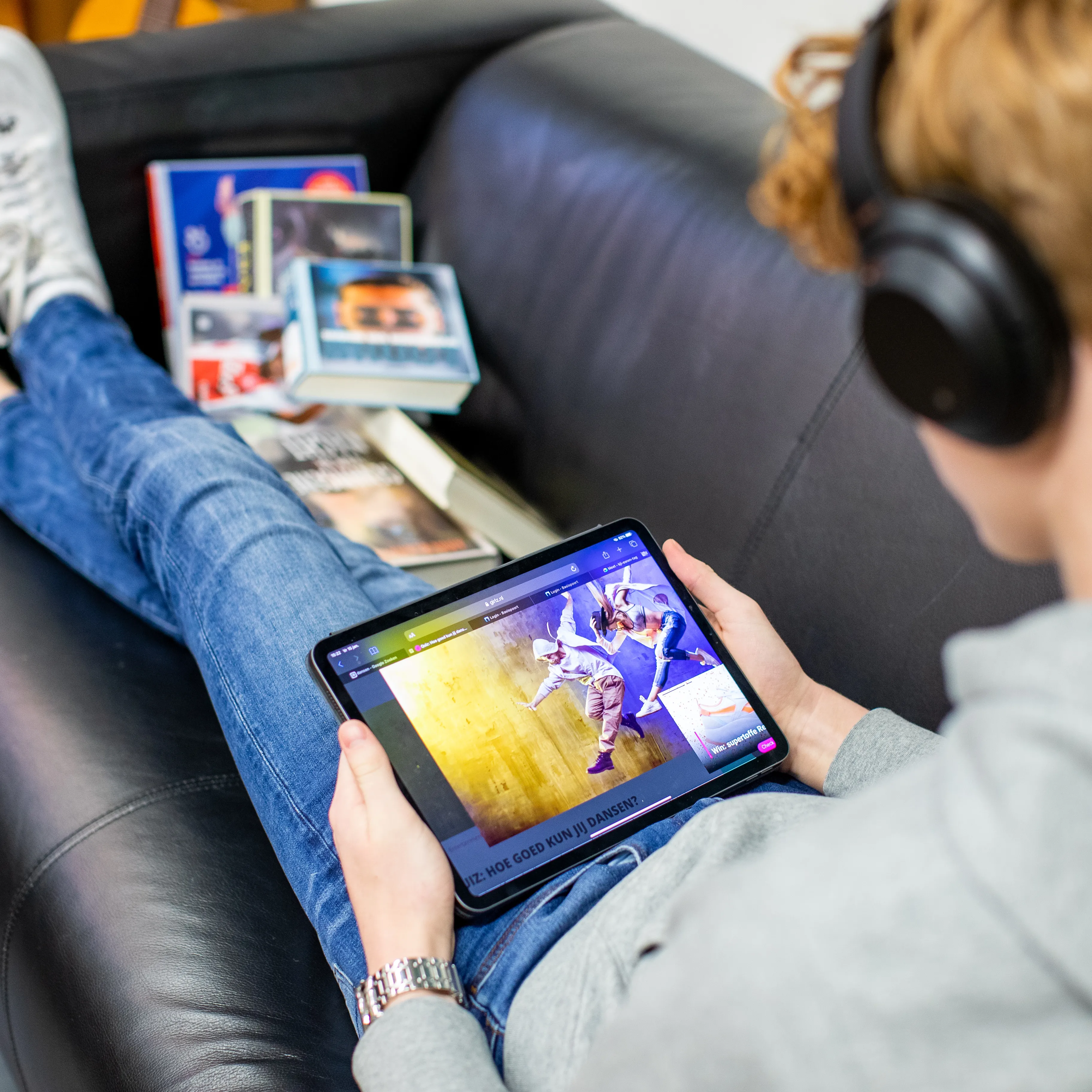 jonge jongen languit op bank met tablet en koptelefoon
