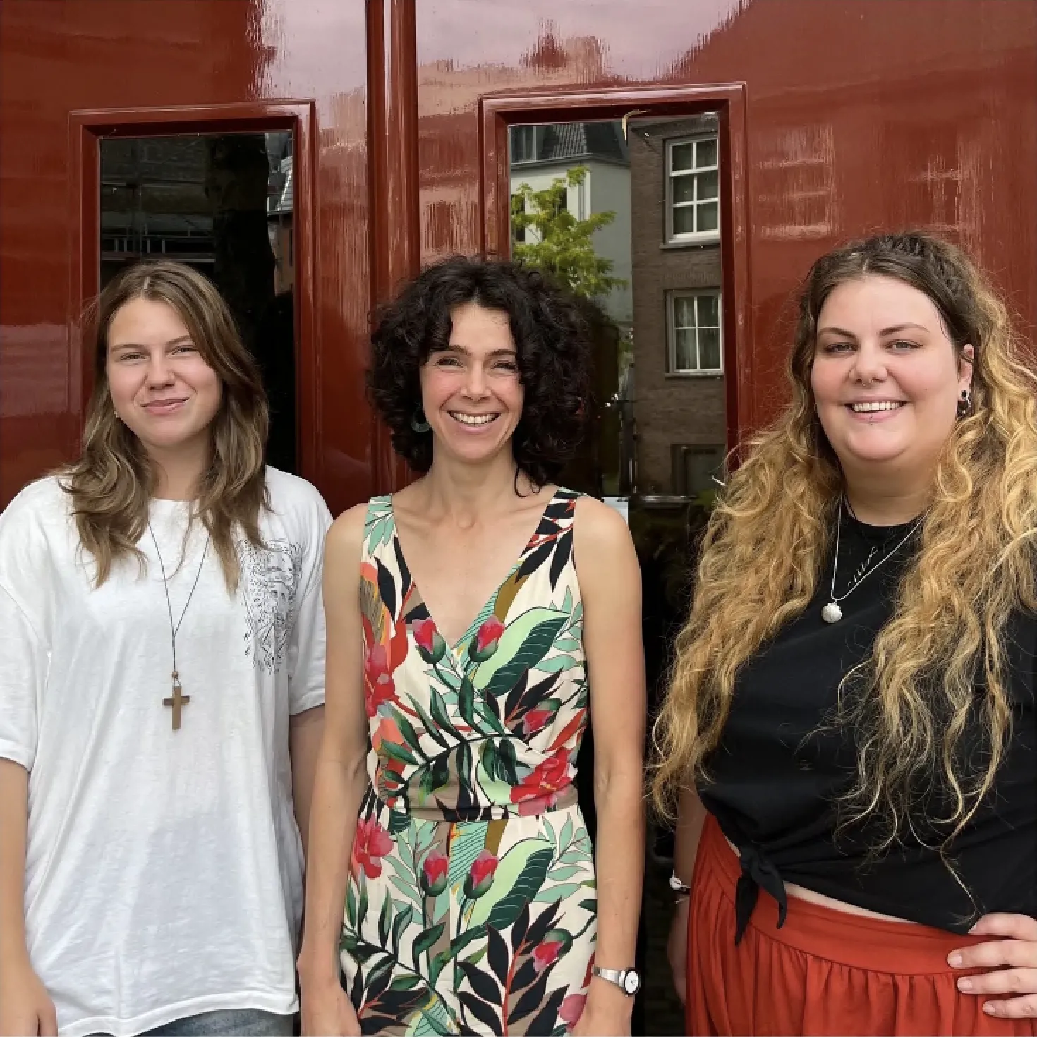 drie jonge vrouwen buiten voor roodbruine deur