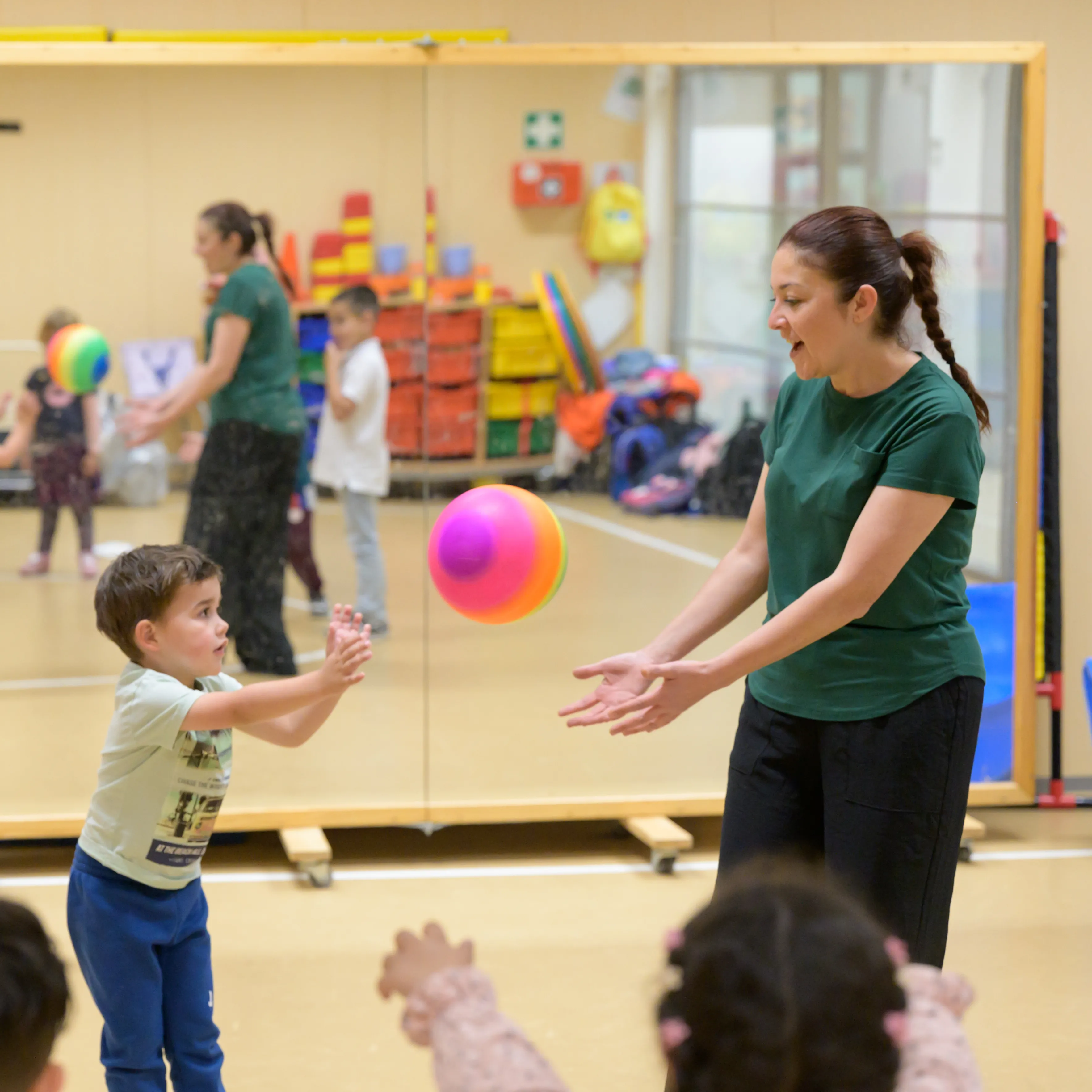 juf met kinderen in gymzaal met bal aan het spelen