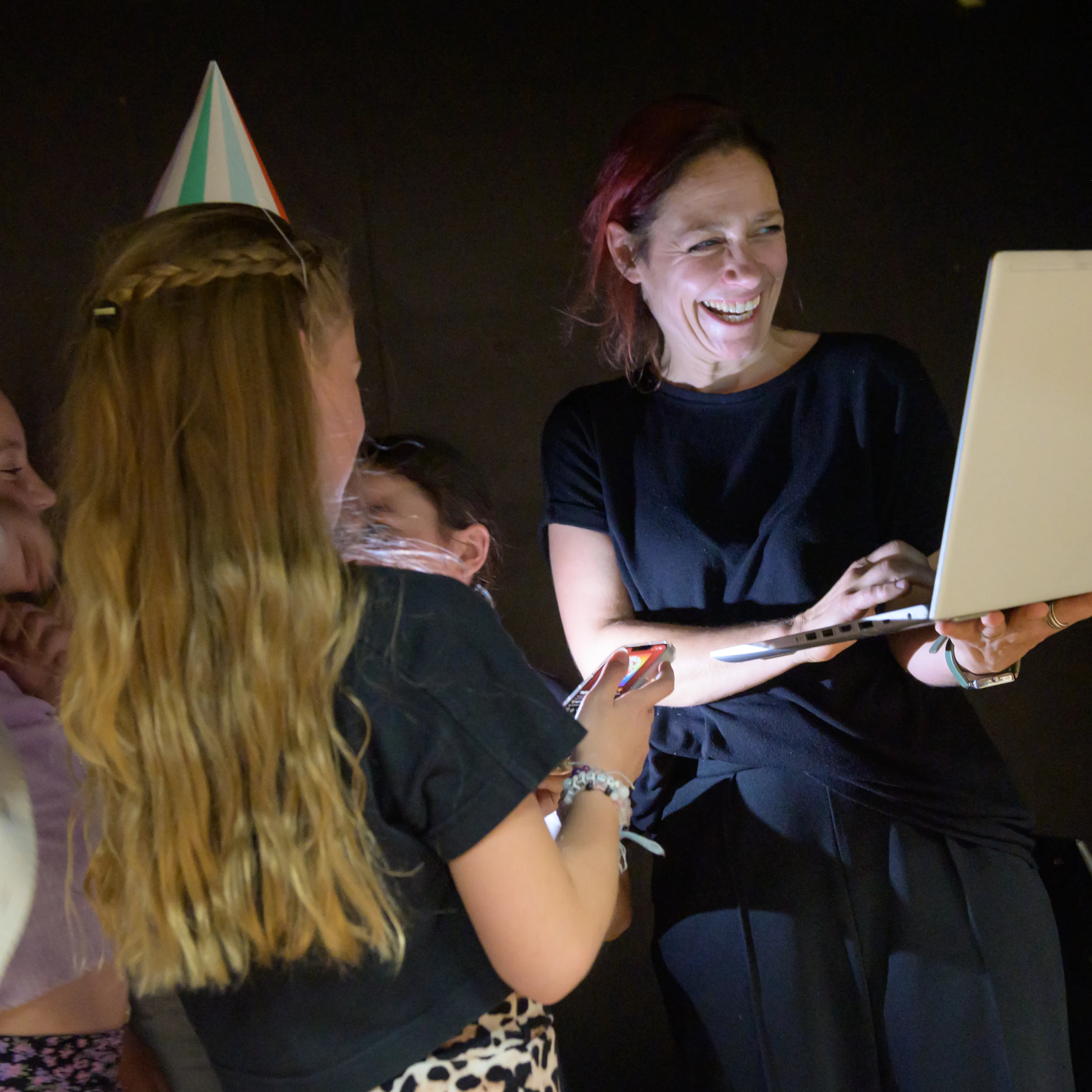Theaterdocent met leerlingen in donkere ruimte met laptop