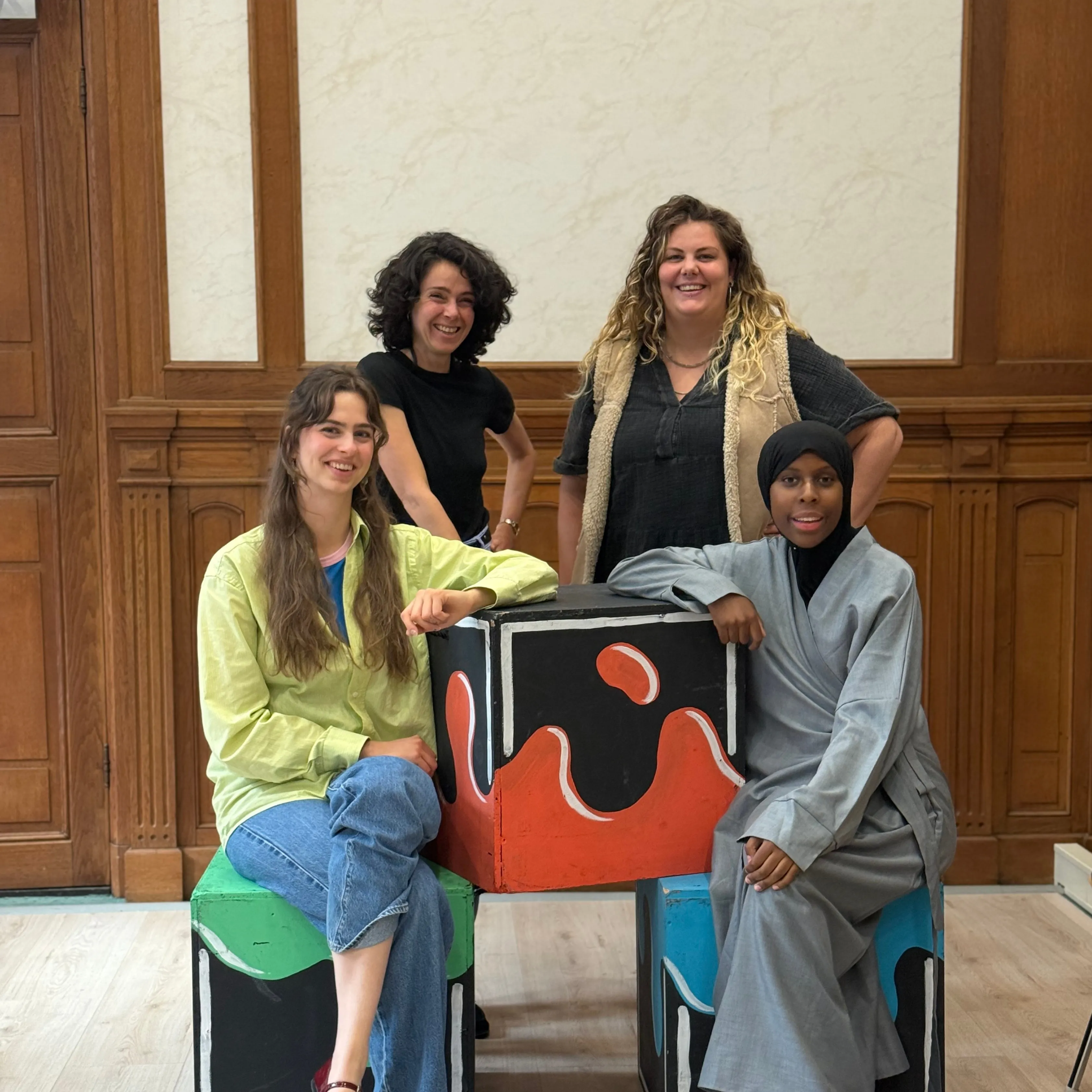 vier dames bij een kleurd blok lachen portret 