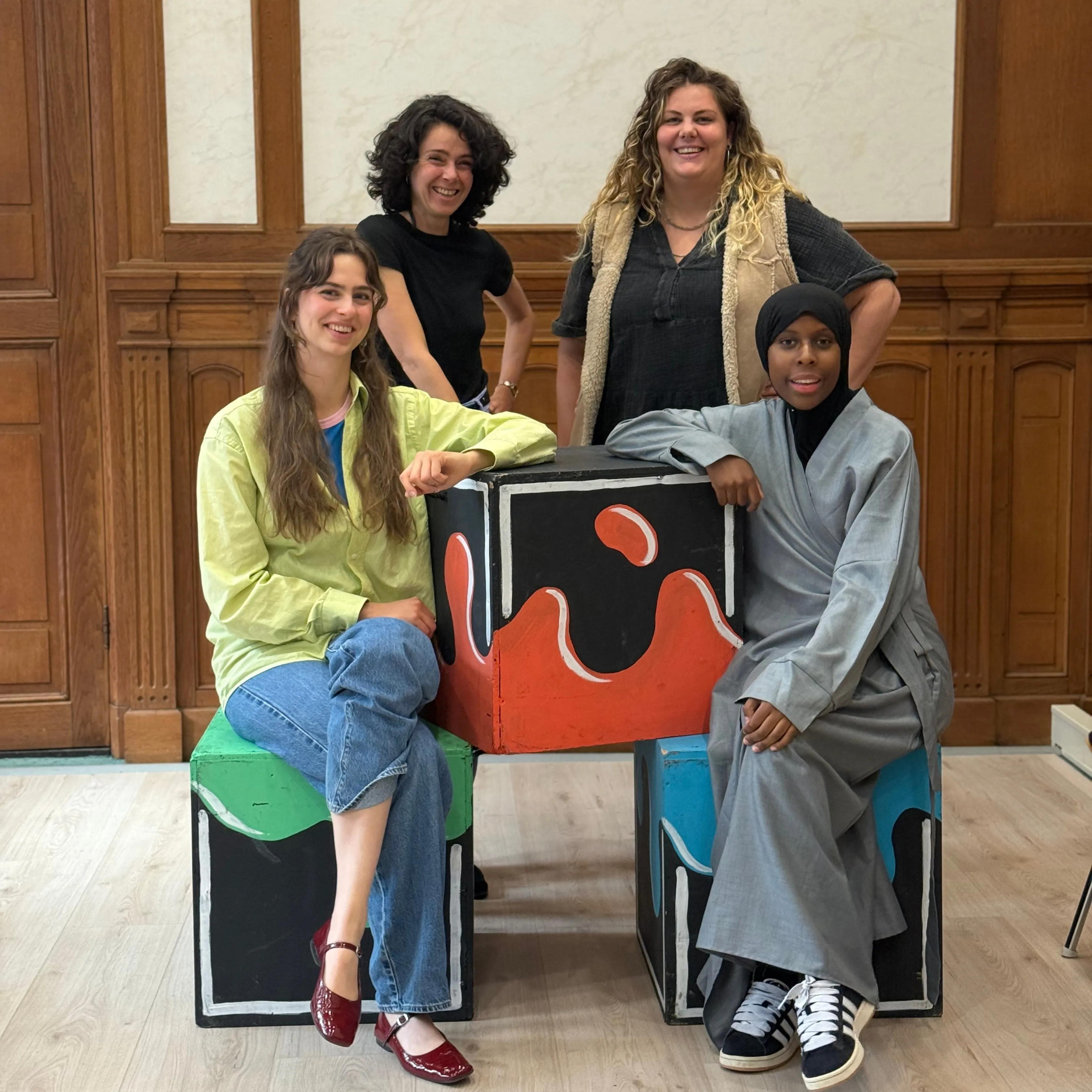 vier dames bij een kleurd blok lachen portret 