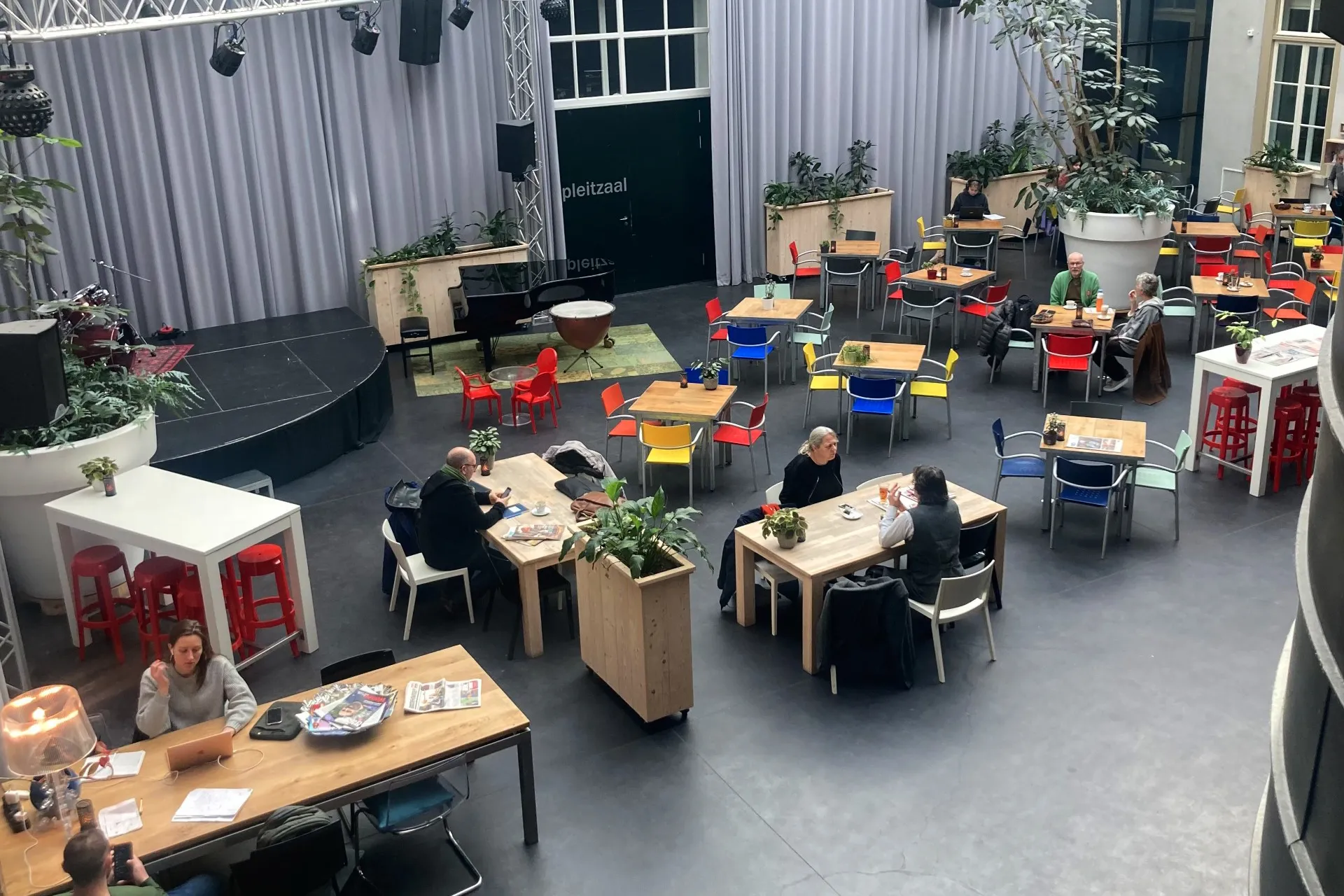 Overzichtsfoto atrium met tafels en werkende mensen
