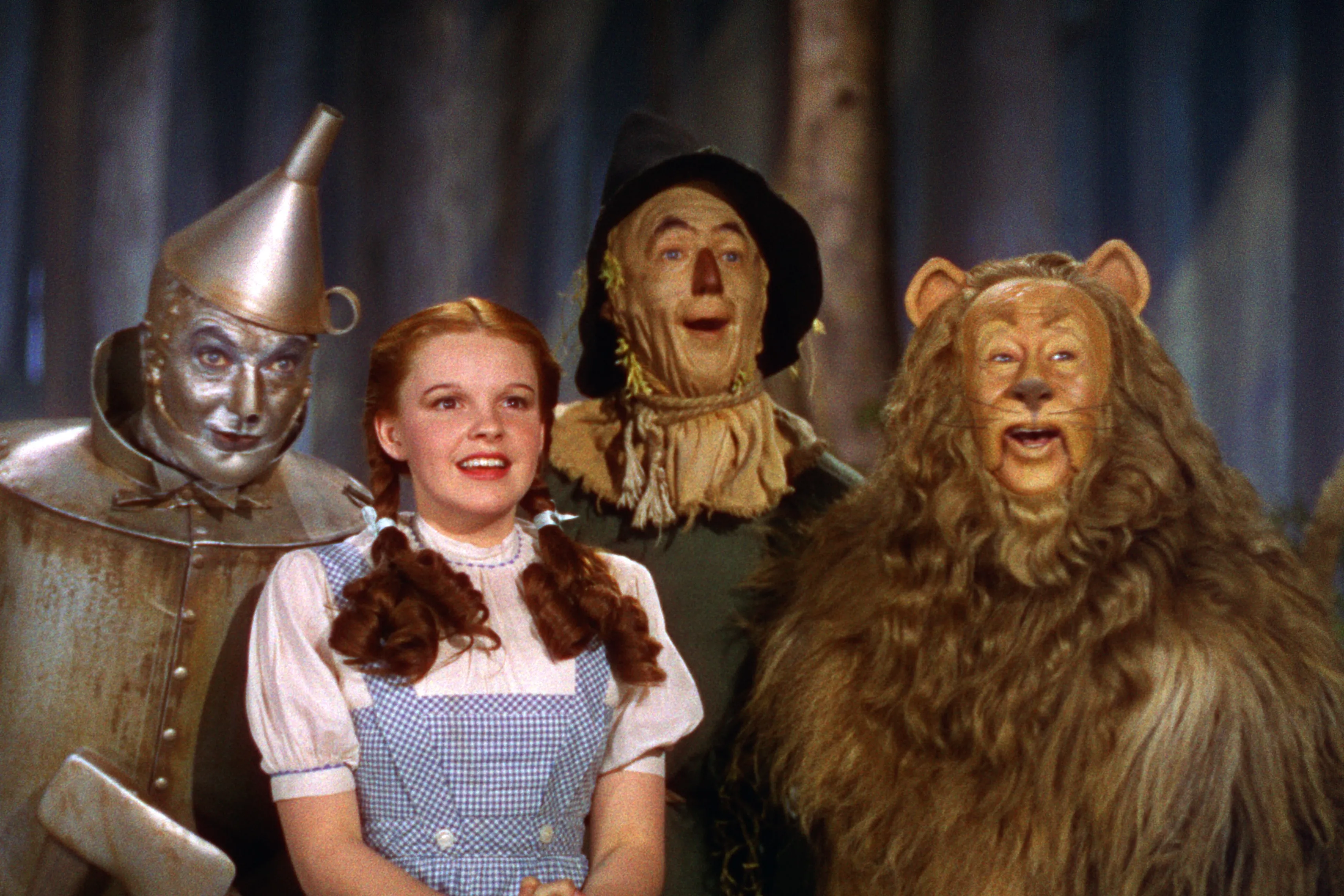 de vier hoofdpersonages van de wizard of oz kijken vrolijk
