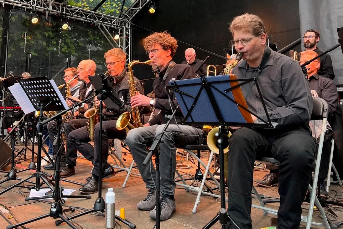 Big band op podium zittend op stoel met instrumenten