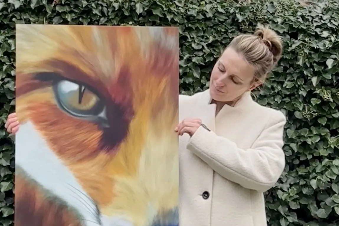 Vrouw met witte jas houdt groot portret vast van vos