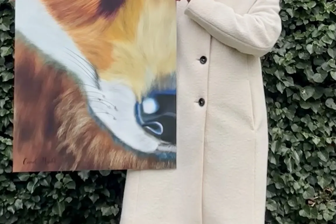 Vrouw met witte jas houdt groot portret vast van vos