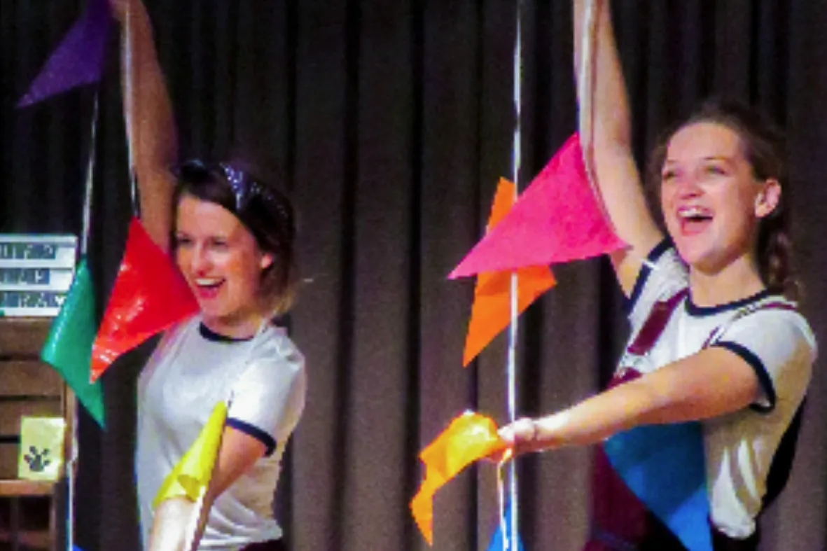 Foto van eerdere show van Letter Belangrijk, waar beide actrices op in beeld zijn met een gekleurde vlaggenslinger