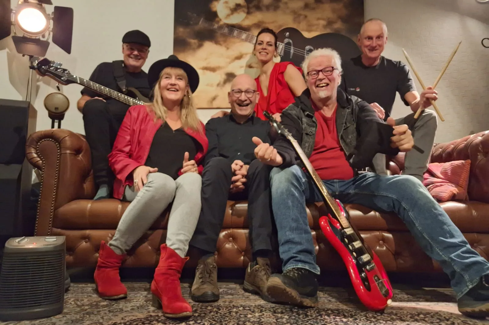 Bandleden met instrumenten zittend op bank