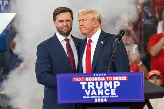 Donald Trump en JD Vance die elkaar de hand schudden.