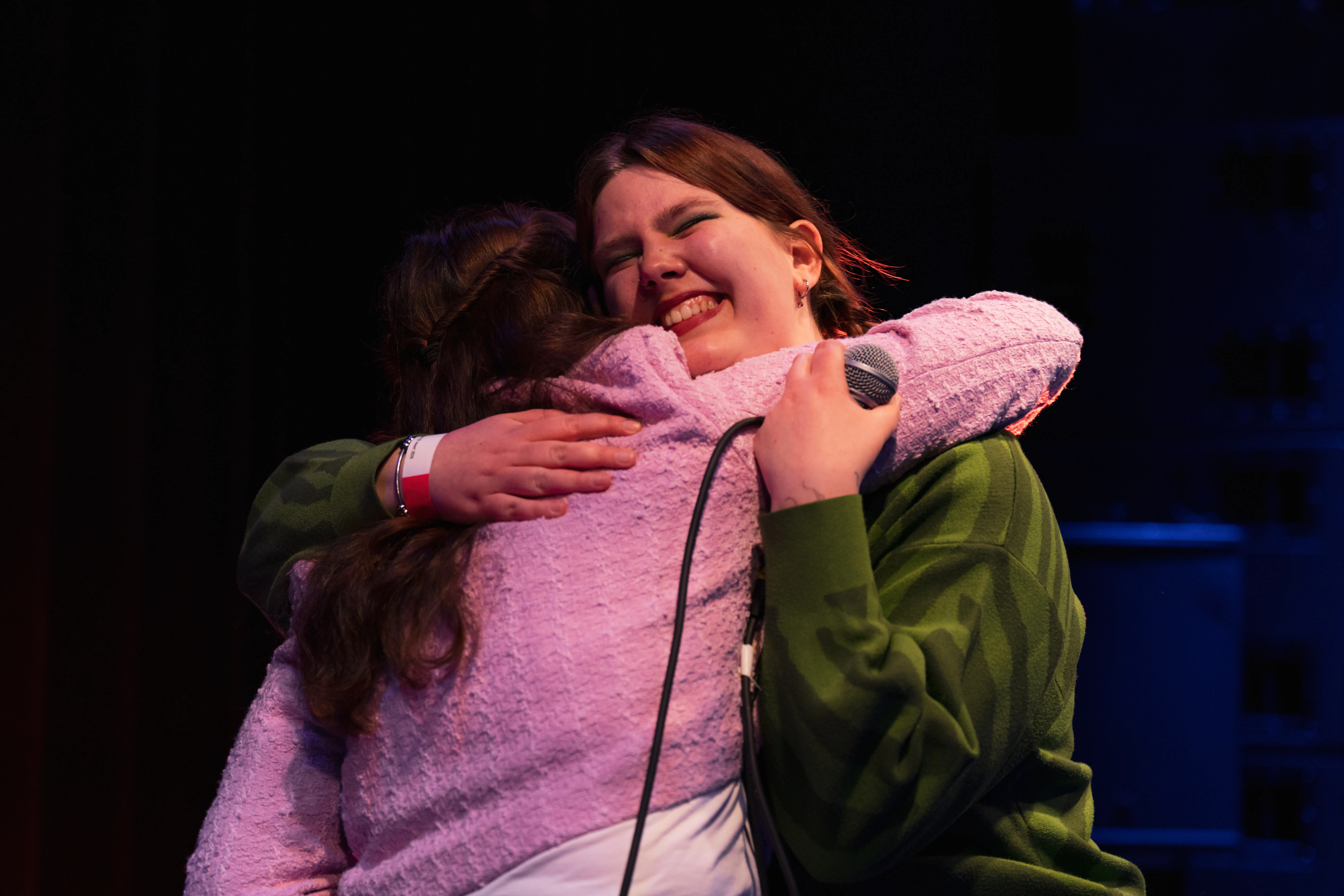 twee jonge vrouwen knuffelen, roze vest, groene trui