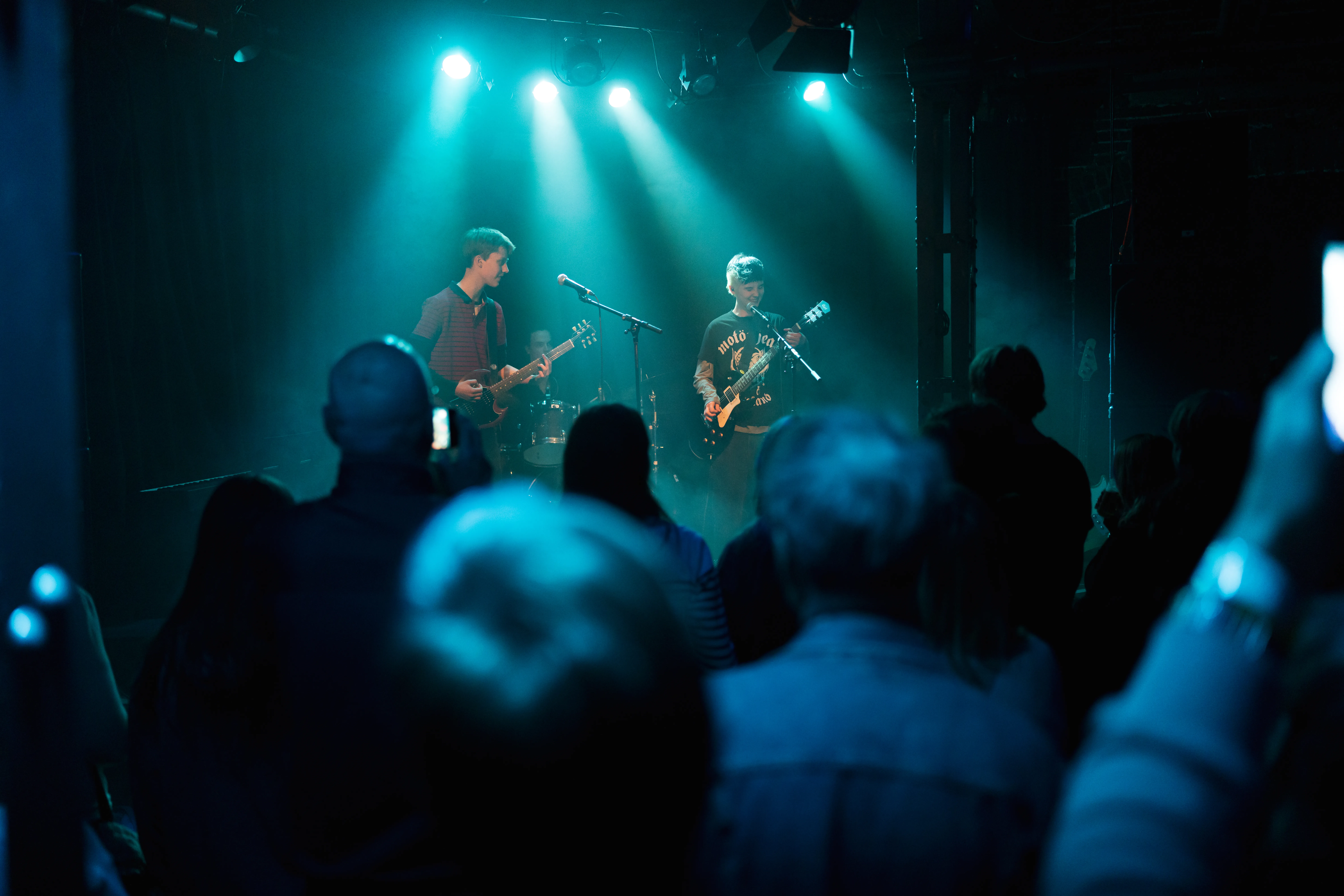 Volle zaal rock band groen blauw licht podium twee personen gitaren en zang