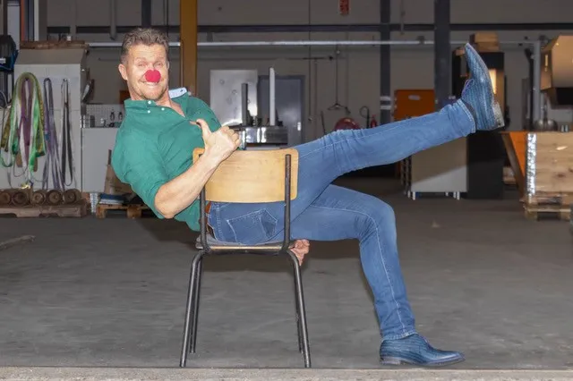 Man op een stoel met een rode clownsneus