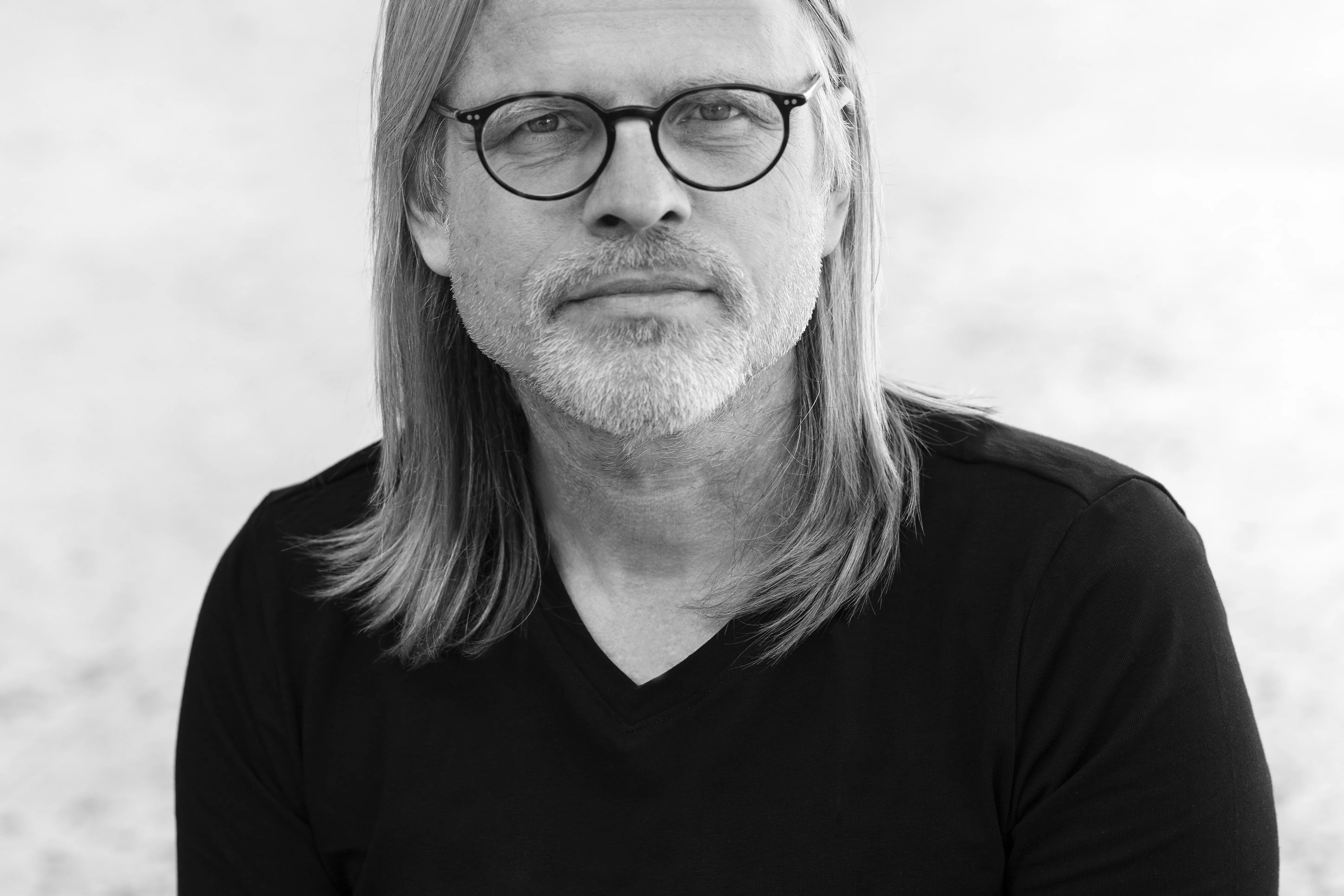 De schrijver is te zien: lang sluik haar, snor en bril. 