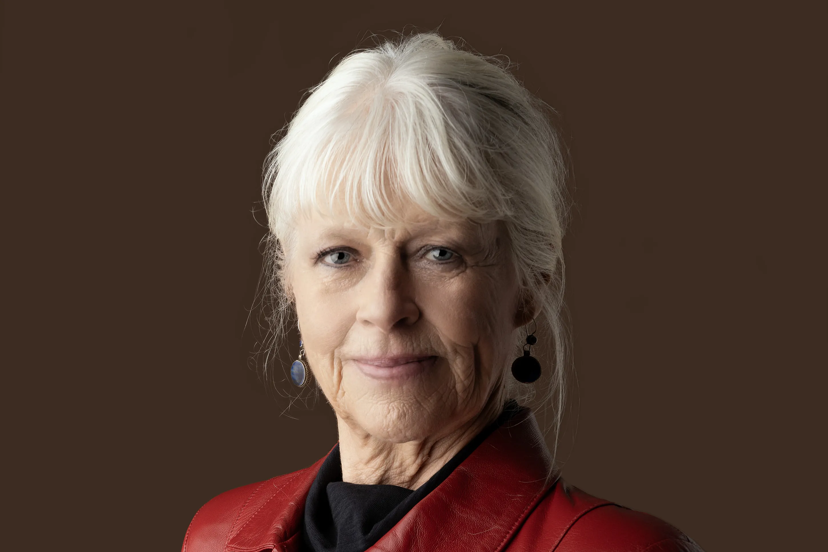 Portret van schrijfster Annegreet van Bergen. Grijze vrouw in rode jas