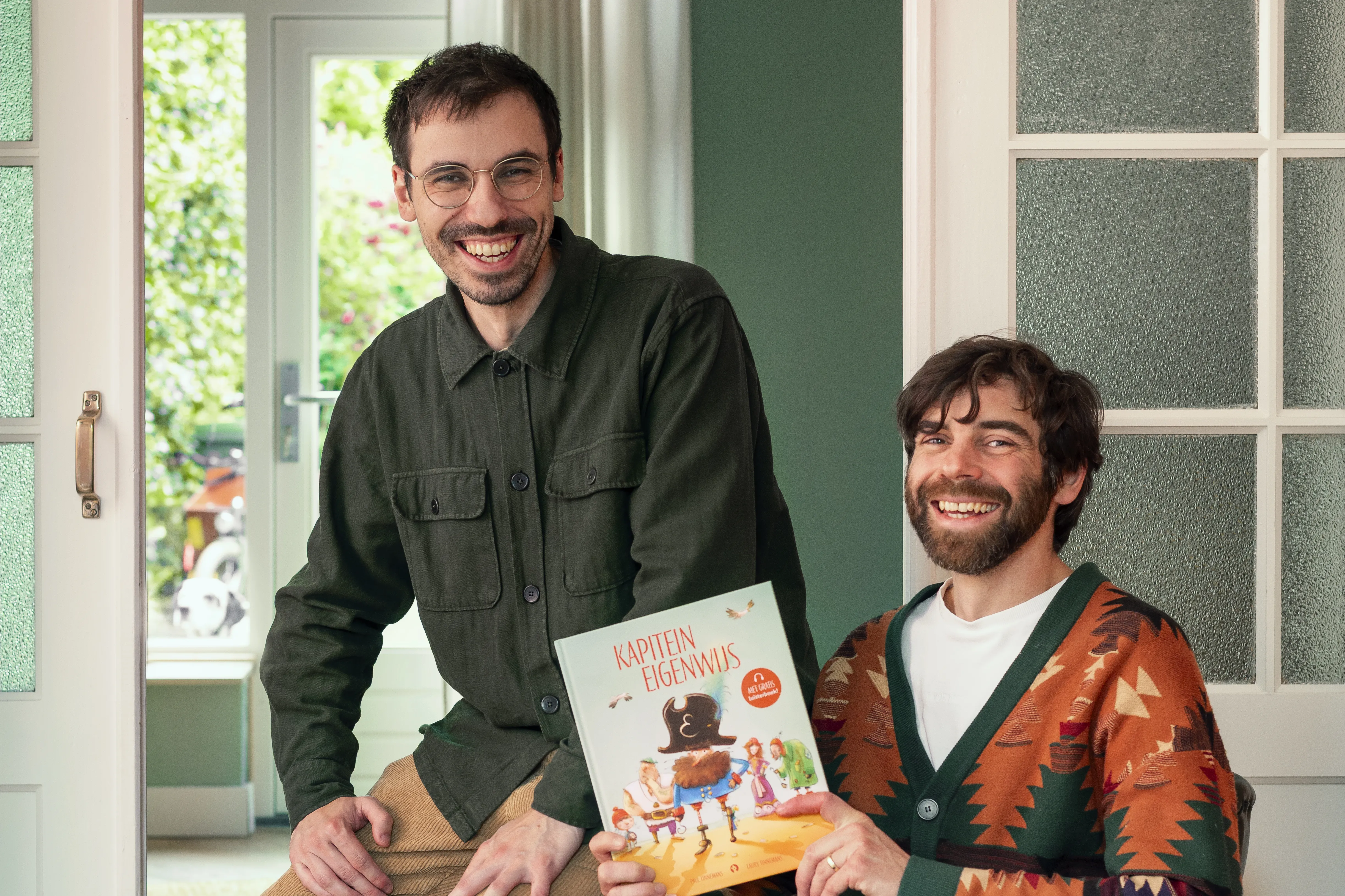Broers Paul en Laury Tinnemans staan samen op de foto met hun zelfgeschreven boek Kapitein Eigenwijs