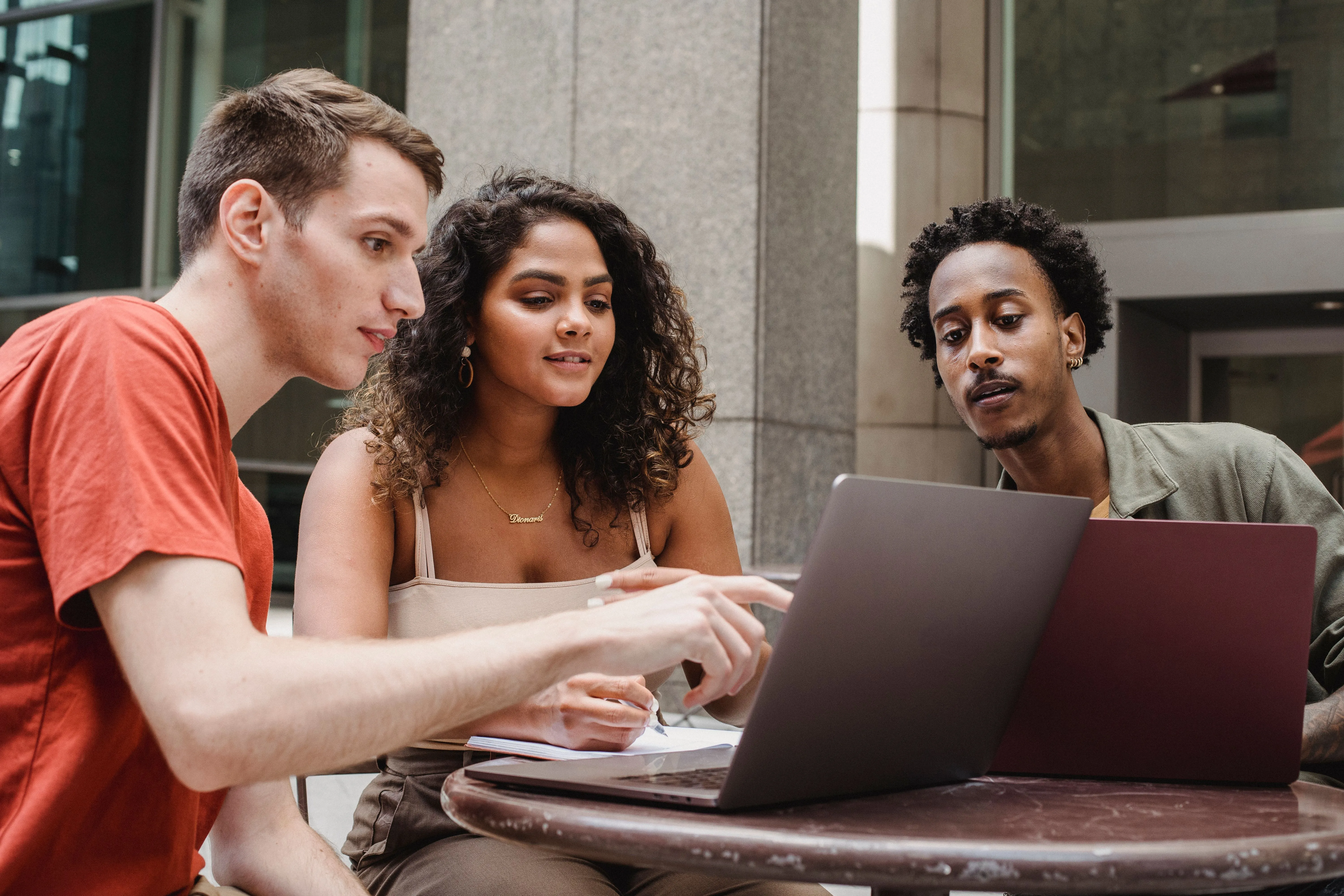 Drie jongeren die samen naar een laptopscherm kijken