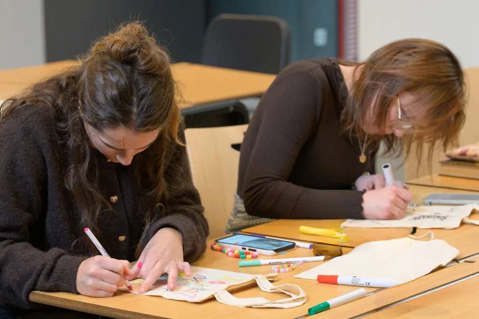 twee jongeren zijn aan het werken aan een tasje kleuren