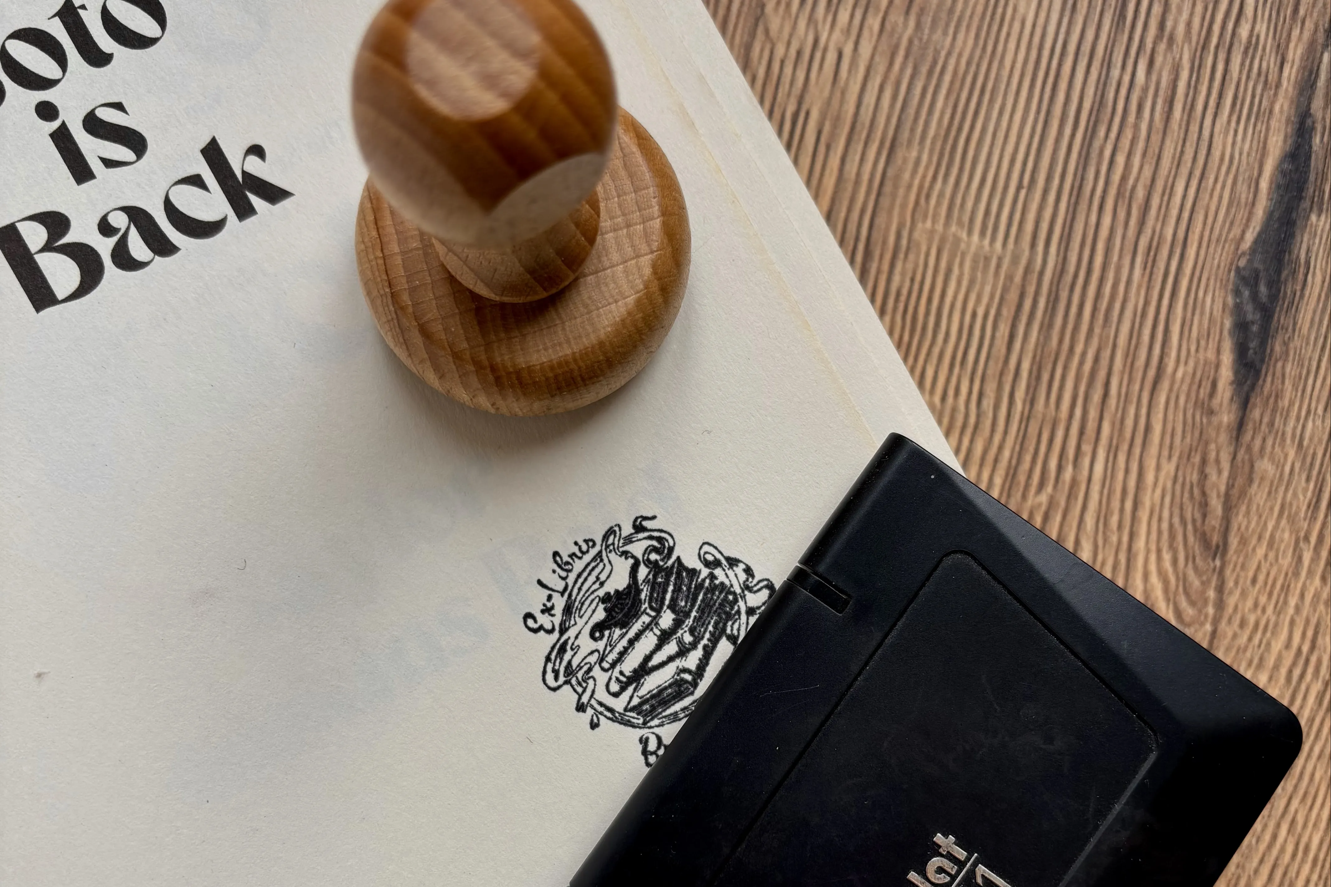pagina van boek met boekenstempel ex libris, inktpad en houten stempel
