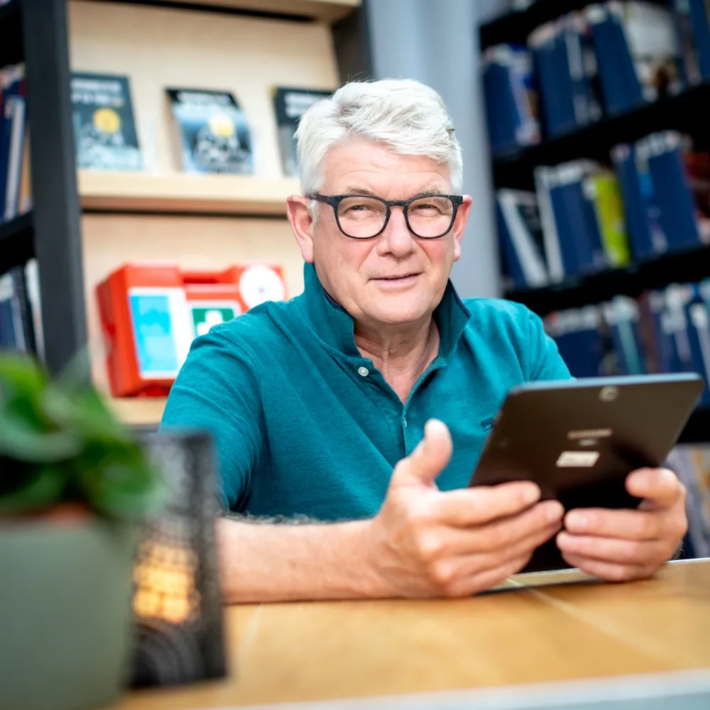 Man met ipad aan tafel 