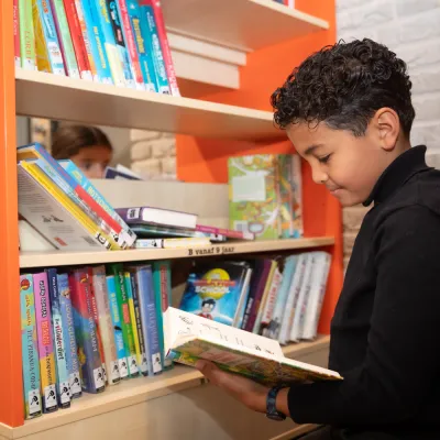 jongen kiest boek uit kast 