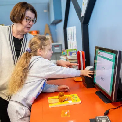 kindje leent boek bij de automaat 