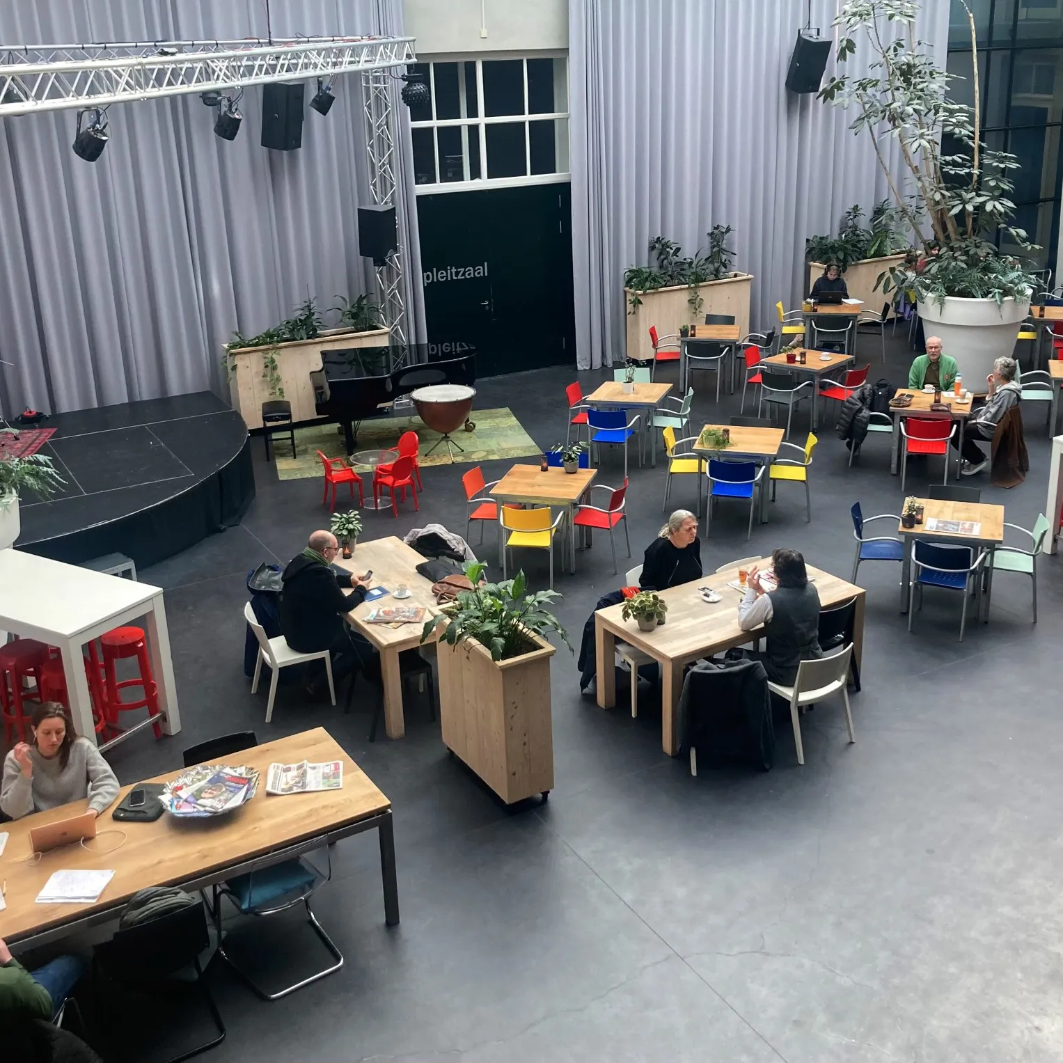 Overzichtsfoto atrium met tafels en werkende mensen
